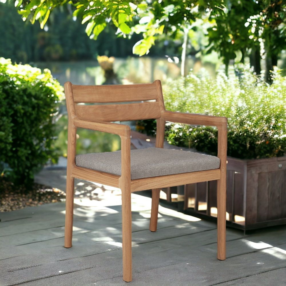 Jack Outdoor Stuhl mit Armlehnen von Ethnicraft: Teakholz Gartenstuhl mit grauem Sitzkissen.