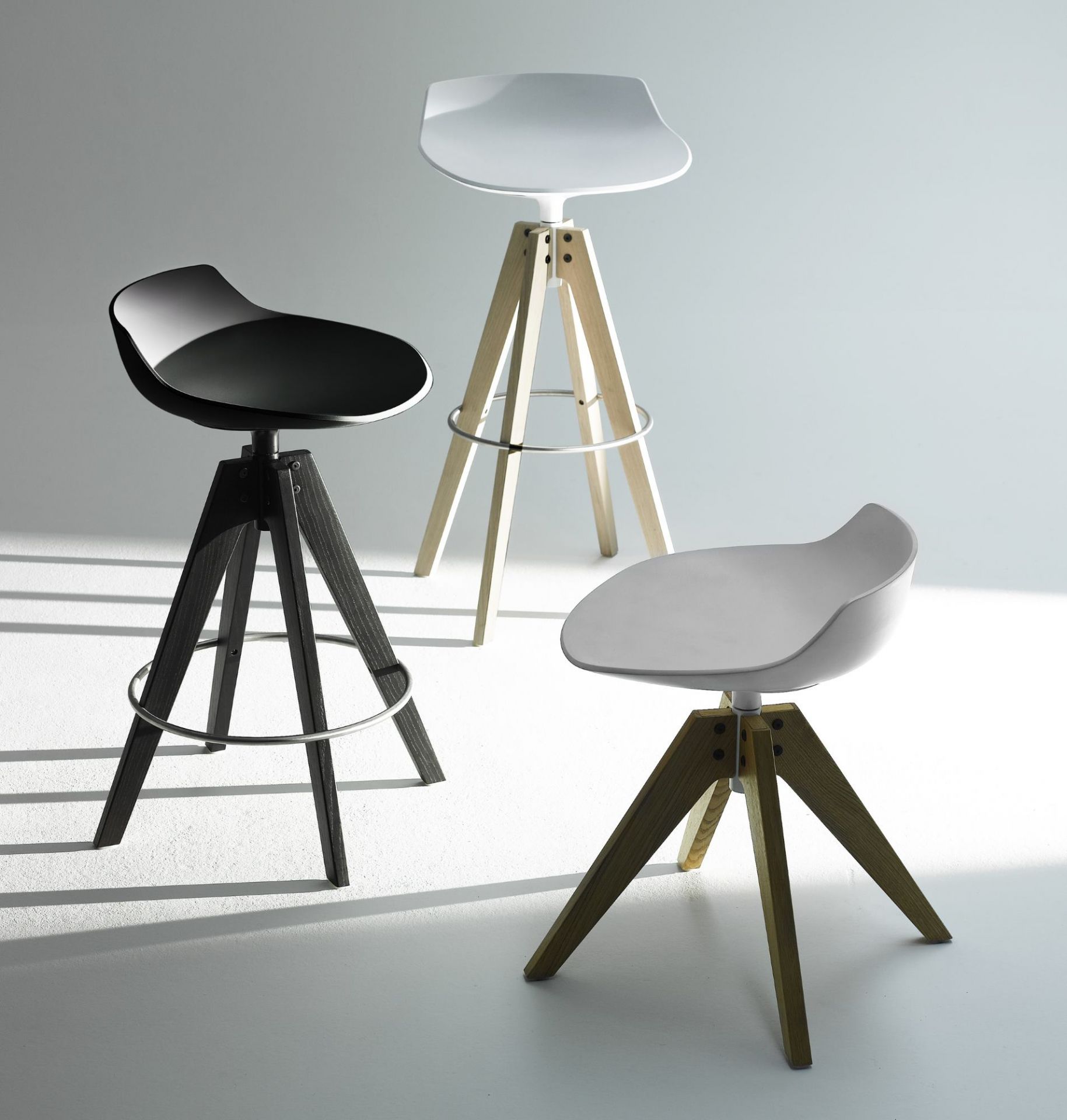 Drei Flow Stool Hocker von MDF Italia in Schwarz, Weiß und Grau mit Holzbeinen.