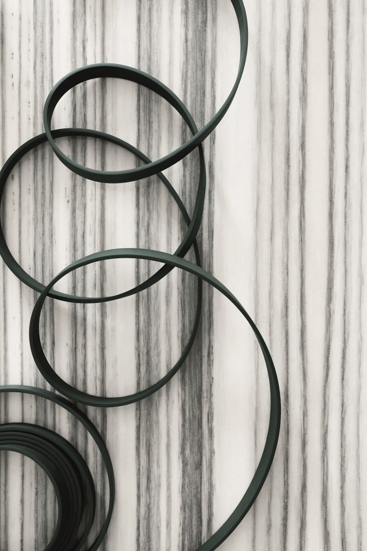 Detailaufnahme der grünen Wireline Pendelleuchte von Flos, moderne Hängeleuchte mit kreisförmigen Elementen vor Marmorwand.