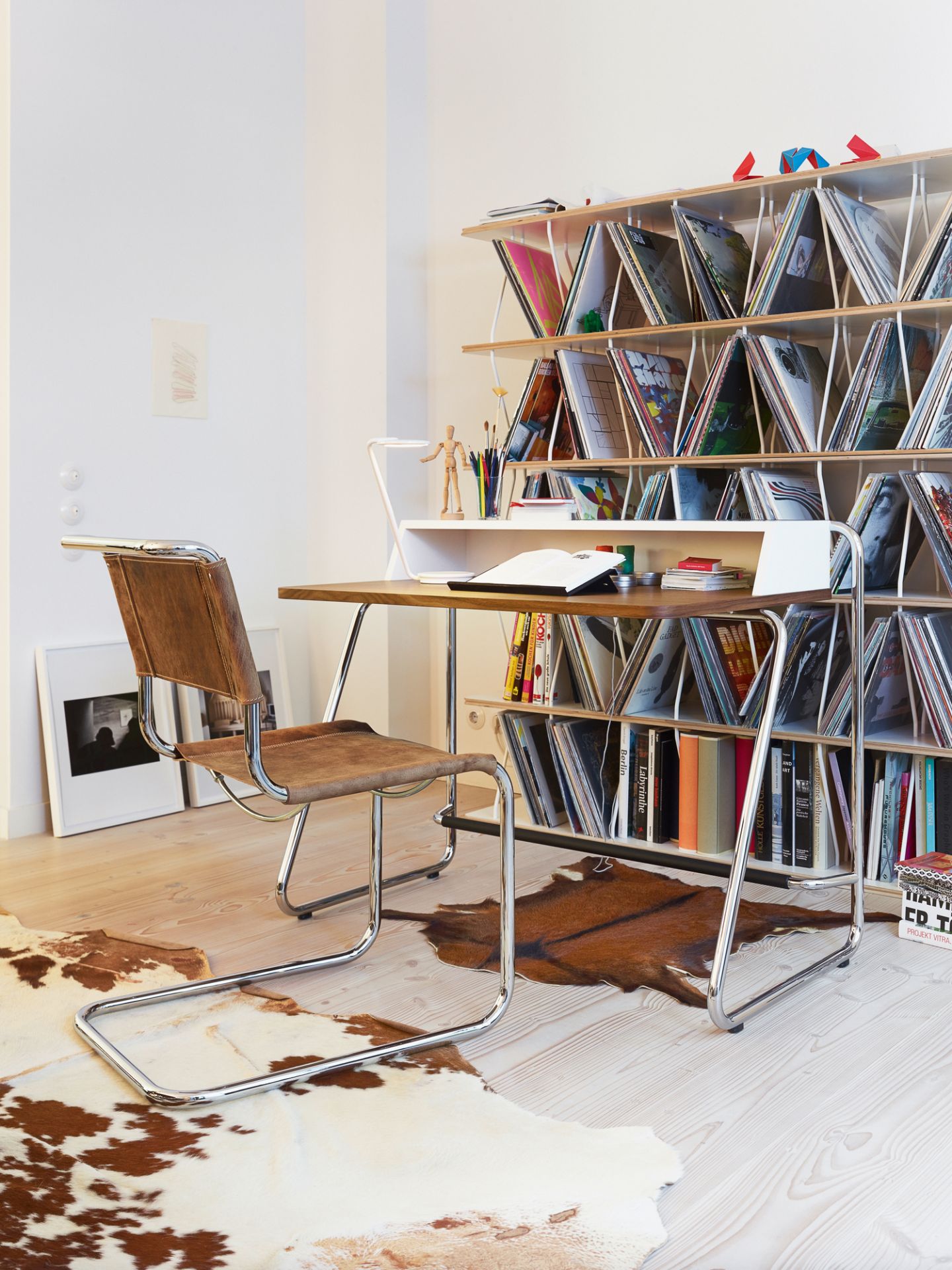 S 1200 Thonet Sekretär mit Stahlrohrgestell und passendem Ledersessel vor Bücherregal.