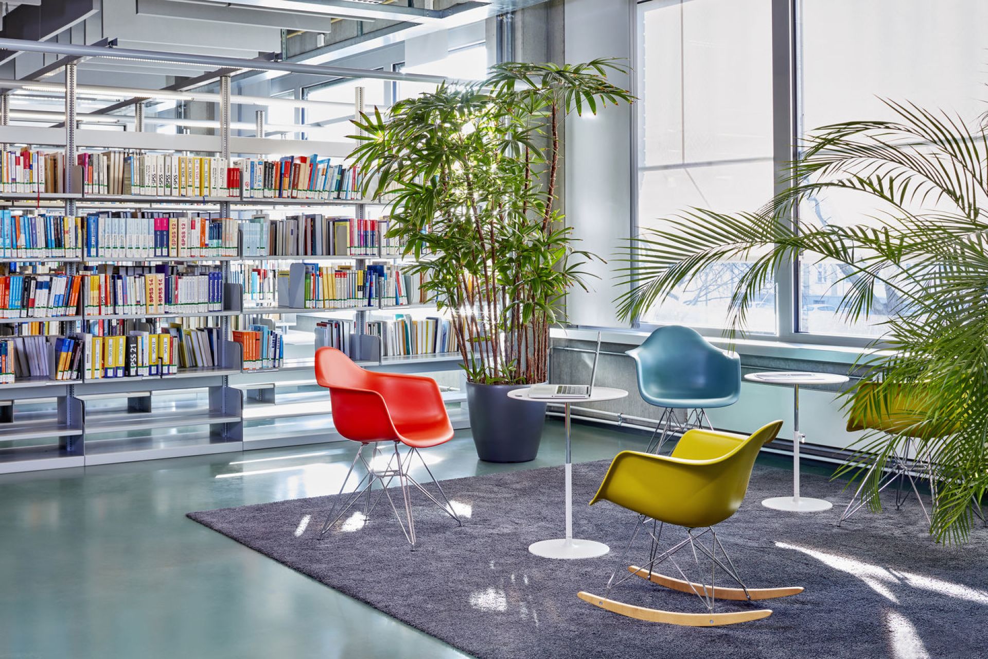 Eames Schaukelstuhl RAR von Vitra in Gelb, Rot und Blau in einer Bibliothek.