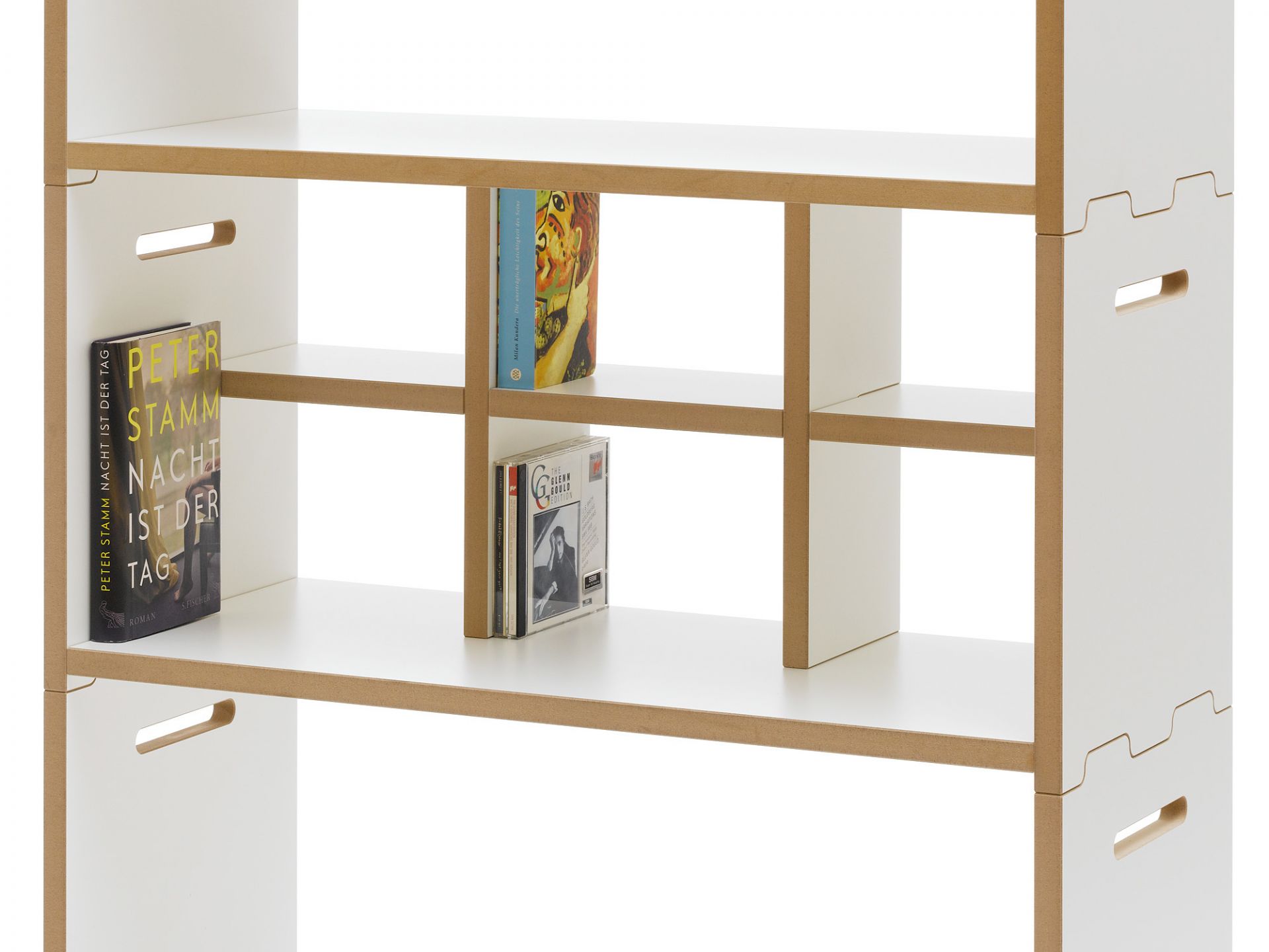 Detailaufnahme des Tojo Hochstapler Regals mit Büchern und CDs, weißes Holzregal.