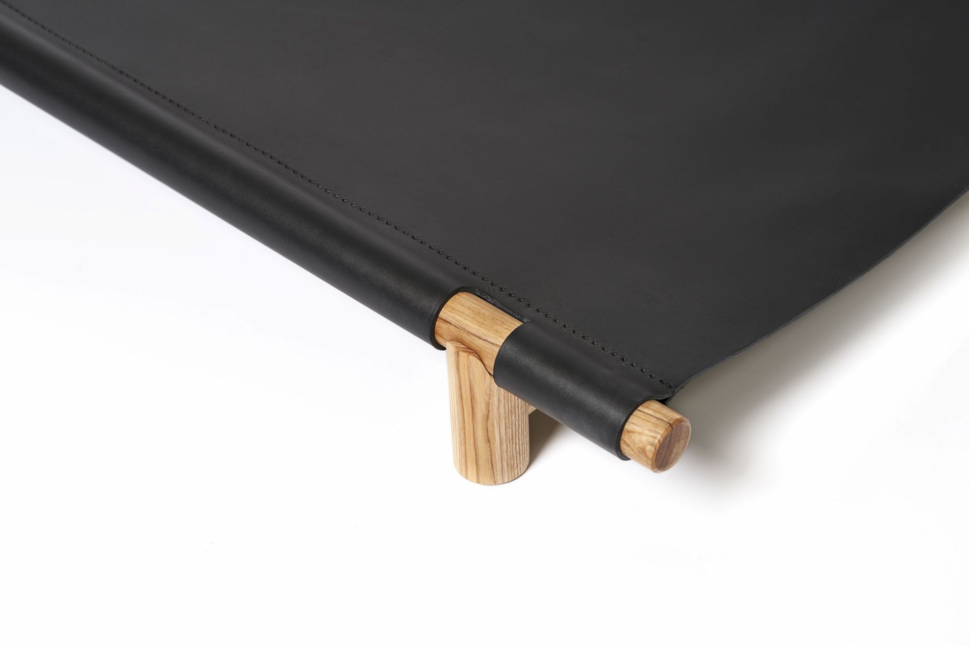 Detailaufnahme: Berberé Hundebett tragbar von Opinion Ciatti, schwarzes Leder mit Holzgestell. Komfortables Reisebett für Hunde.