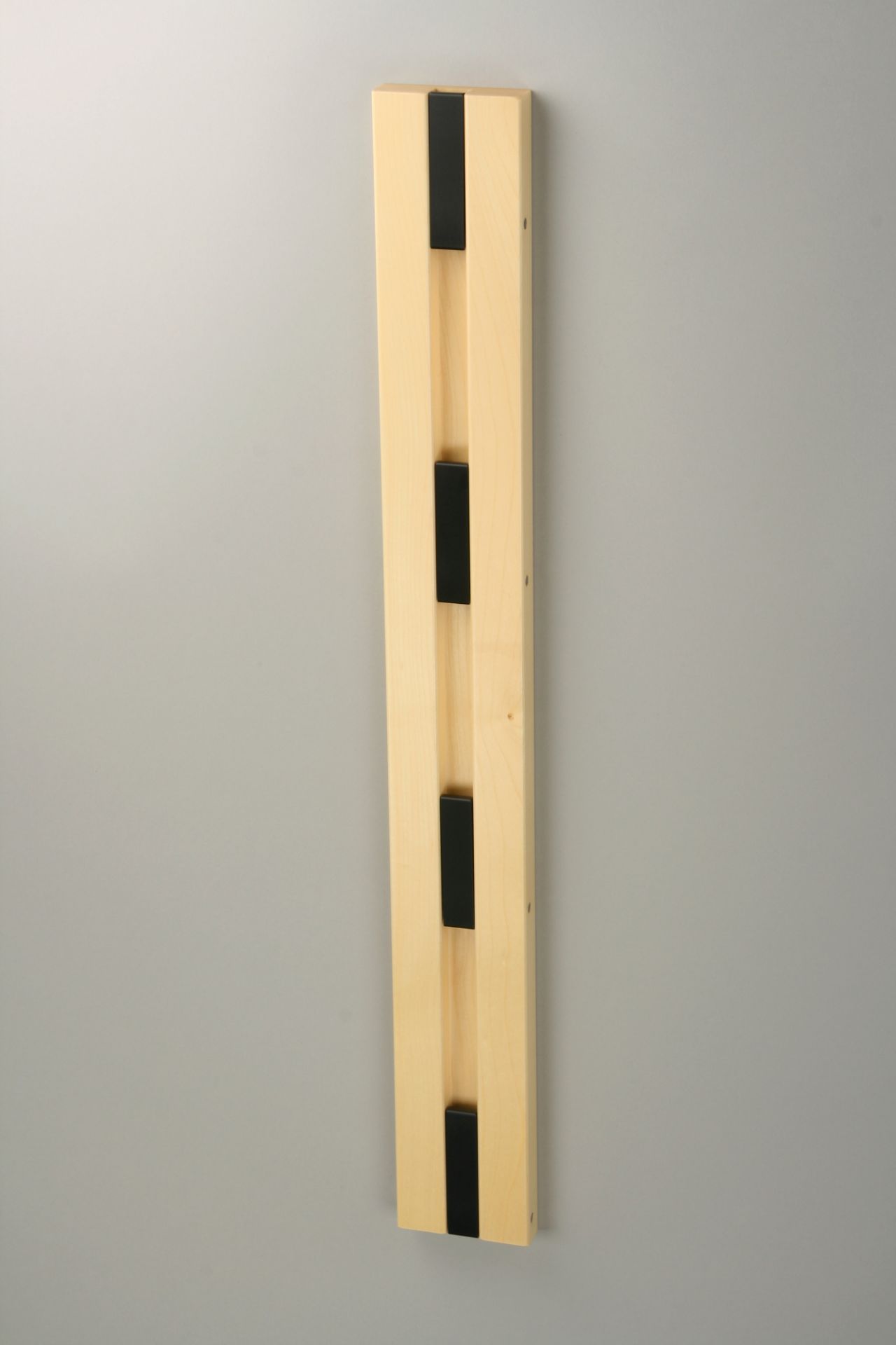Knax Wandgarderobe mit vier schwarzen Haken an einer vertikalen Holzleiste, moderne Garderobenlösung.