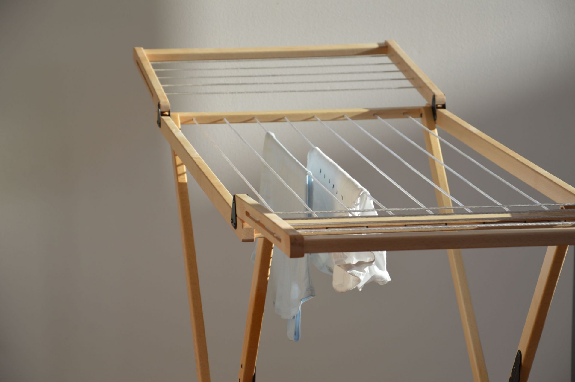 Vivo Wäscheständer Jan Kurtz aus Holz mit aufgehängter, weißer Wäsche vor hellem Hintergrund.