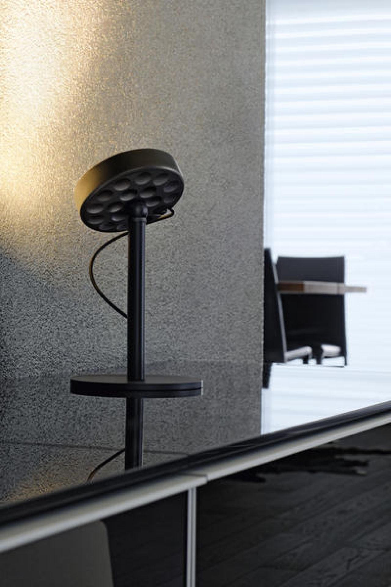 Schwarze Belux U-Turn Tischleuchte mit rundem Lampenkopf und Fuß auf einem dunklen Tisch.