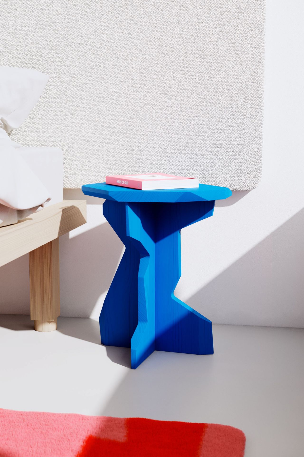 Blauer FELS Hocker aus Esche, modernes Design, mit Buch auf der Sitzfläche.