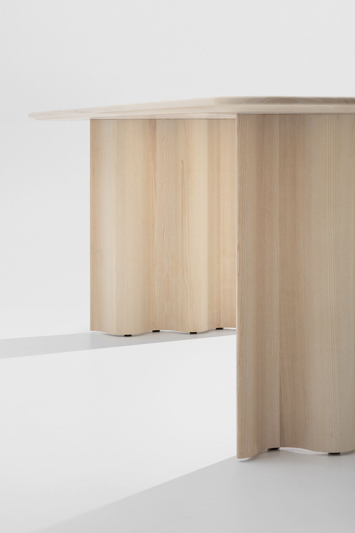 Detailaufnahme des Curtain Tisches: Rechteckiger Esstisch aus hellem Holz mit wellenförmigen Beinen.