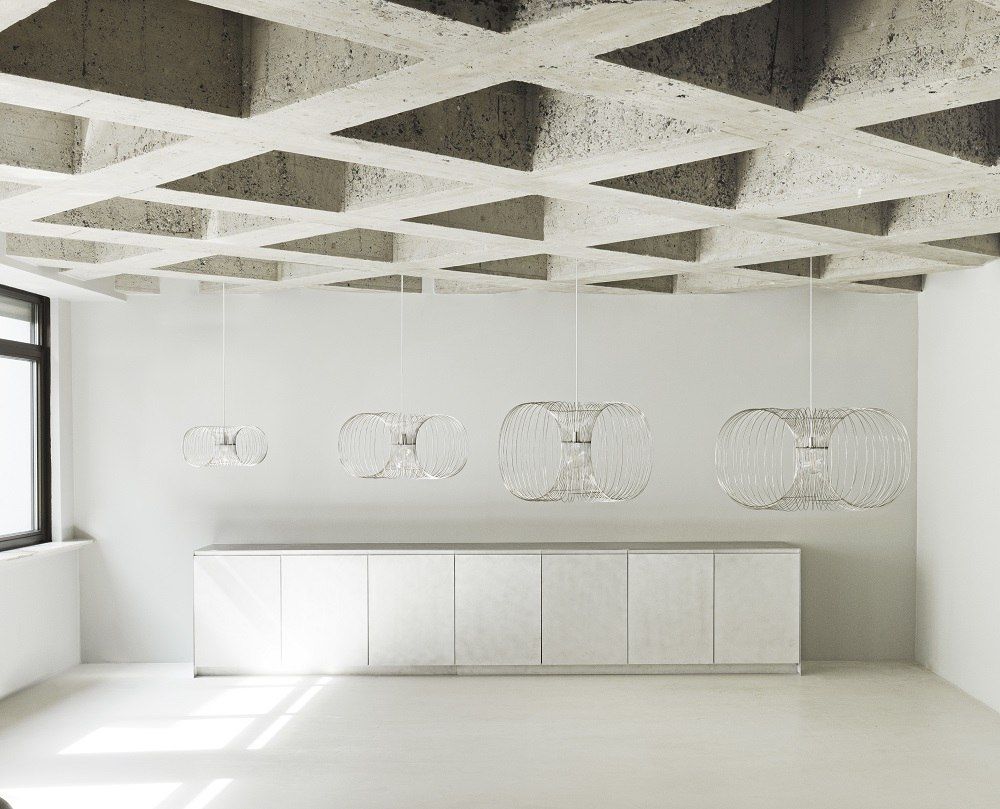 Coil Lampe von Normann Copenhagen: Vier moderne Pendelleuchten in verschiedenen Größen über einem Sideboard.