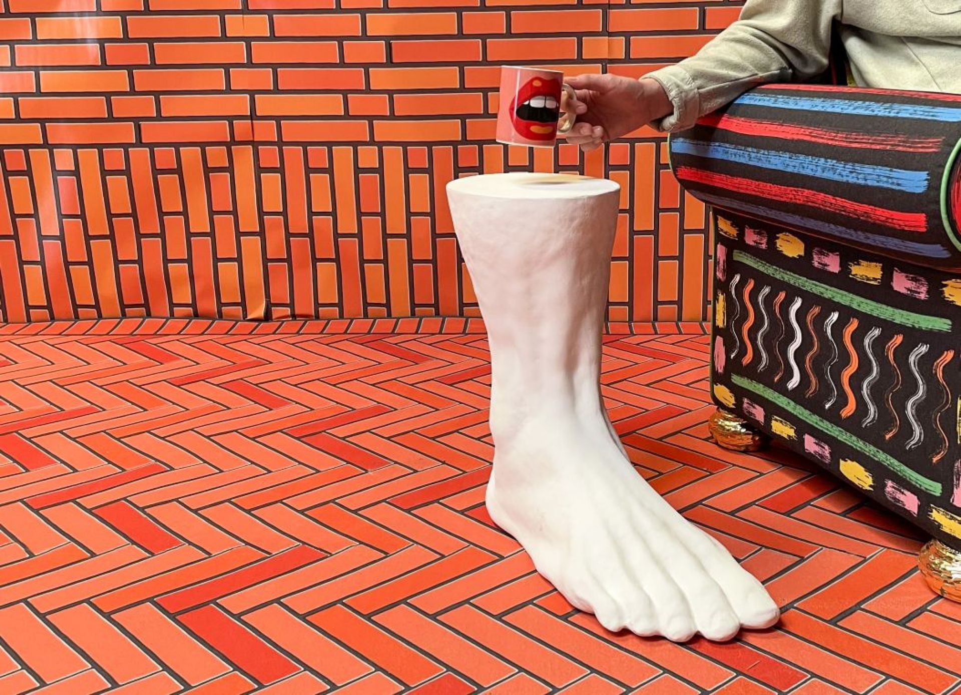 Weißer Colossus Beistelltisch von Seletti in Form eines Fußes, mit Tasse und Sofa.