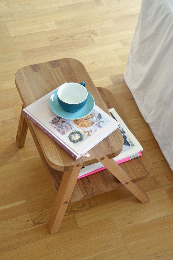 Oli Tritthocker von Jan Kurtz aus Holz mit Buch und Teetasse.