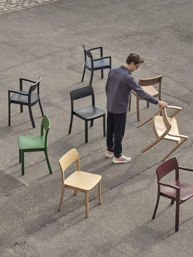 Mehrere Hay Pastis Stühle in verschiedenen Farben, darunter stahlblau, Esche und Holz, im Freien.