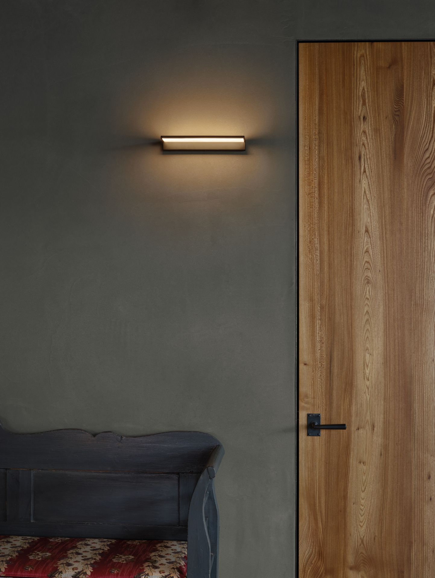 Moderne Crib Wall Wandleuchte von Serien Lighting aus Edelstahl an grauer Wand.