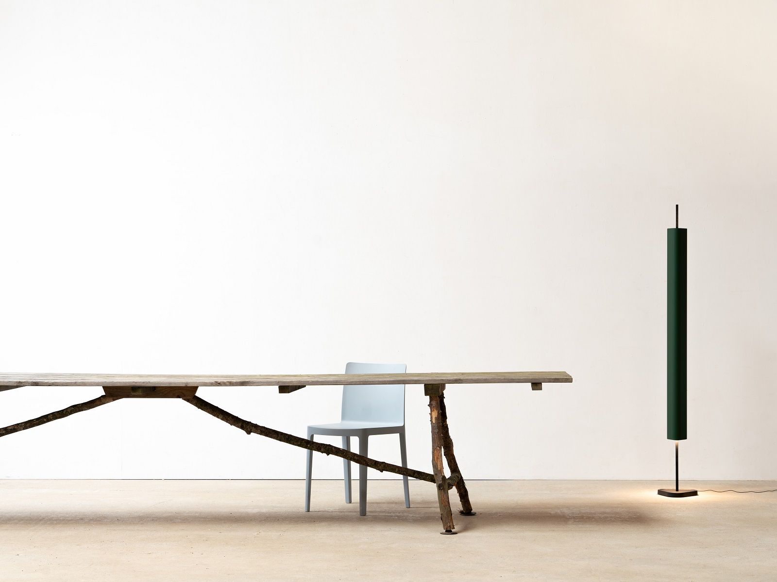 Emi Floor Stehleuchte von Flos, all in Weiß, neben einem Holztisch und Stuhl.