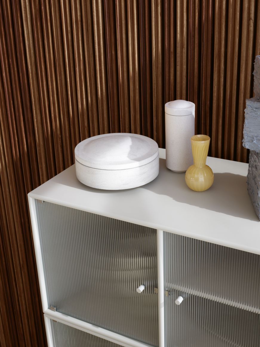 Detailaufnahme: Ripple III Vitrinenschrank in Truffle mit schwarzem Gestell und geriffelten Glastüren.