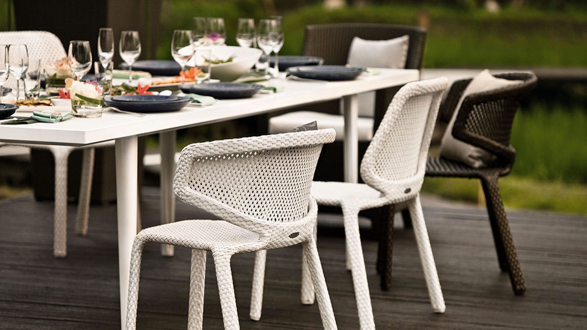 Nahaufnahme des weißen Dedon Seashell Armlehnstuhls am Esstisch im Freien.