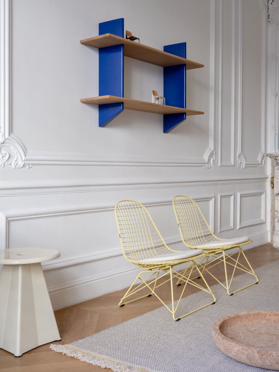 Beiger Tabouret Métallique Hocker von Vitra neben gelben Drahtstühlen in stilvollem Interieur.