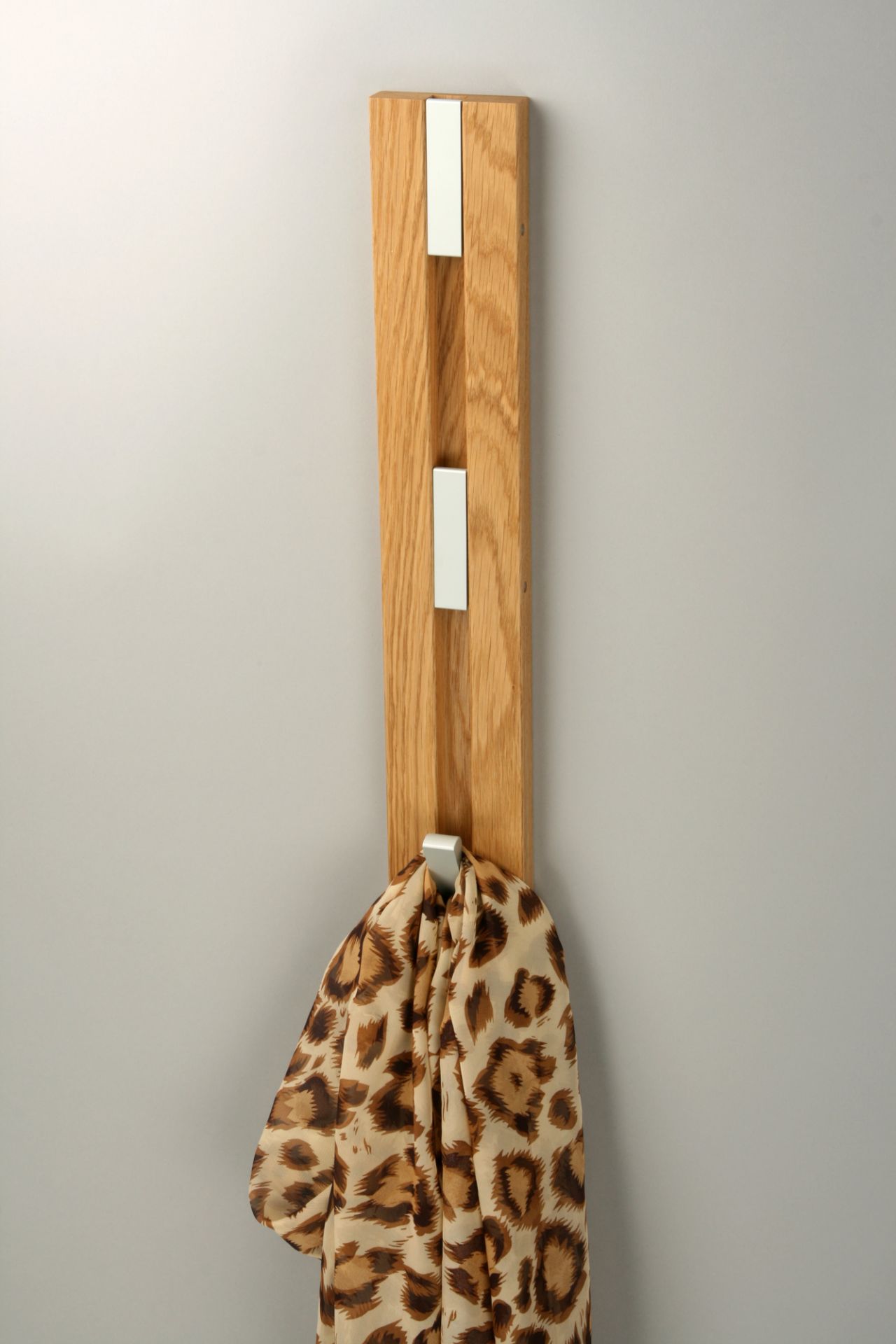 Knax Wandgarderobe mit vier Haken aus Holz, vertikal an der Wand montiert, mit Schal.