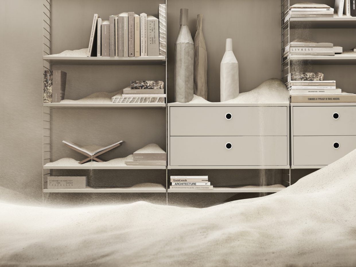 Helles String Regal mit Bücher, Deko und Sand. Arbeitsplatz mit Stauraum.