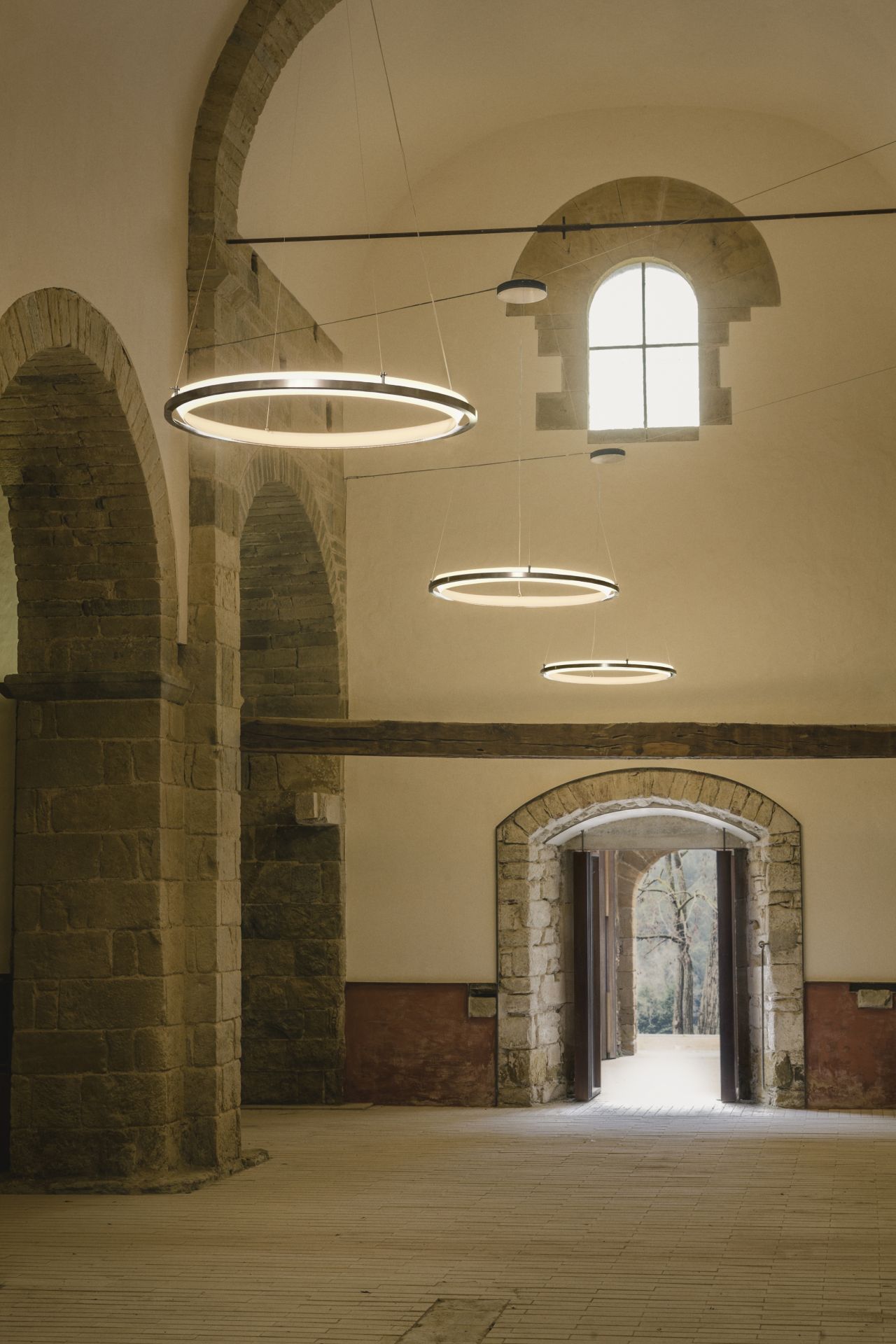 Innenaufnahme mit drei runden Nimba Pendelleuchten von Santa & Cole, hängend im Raum.