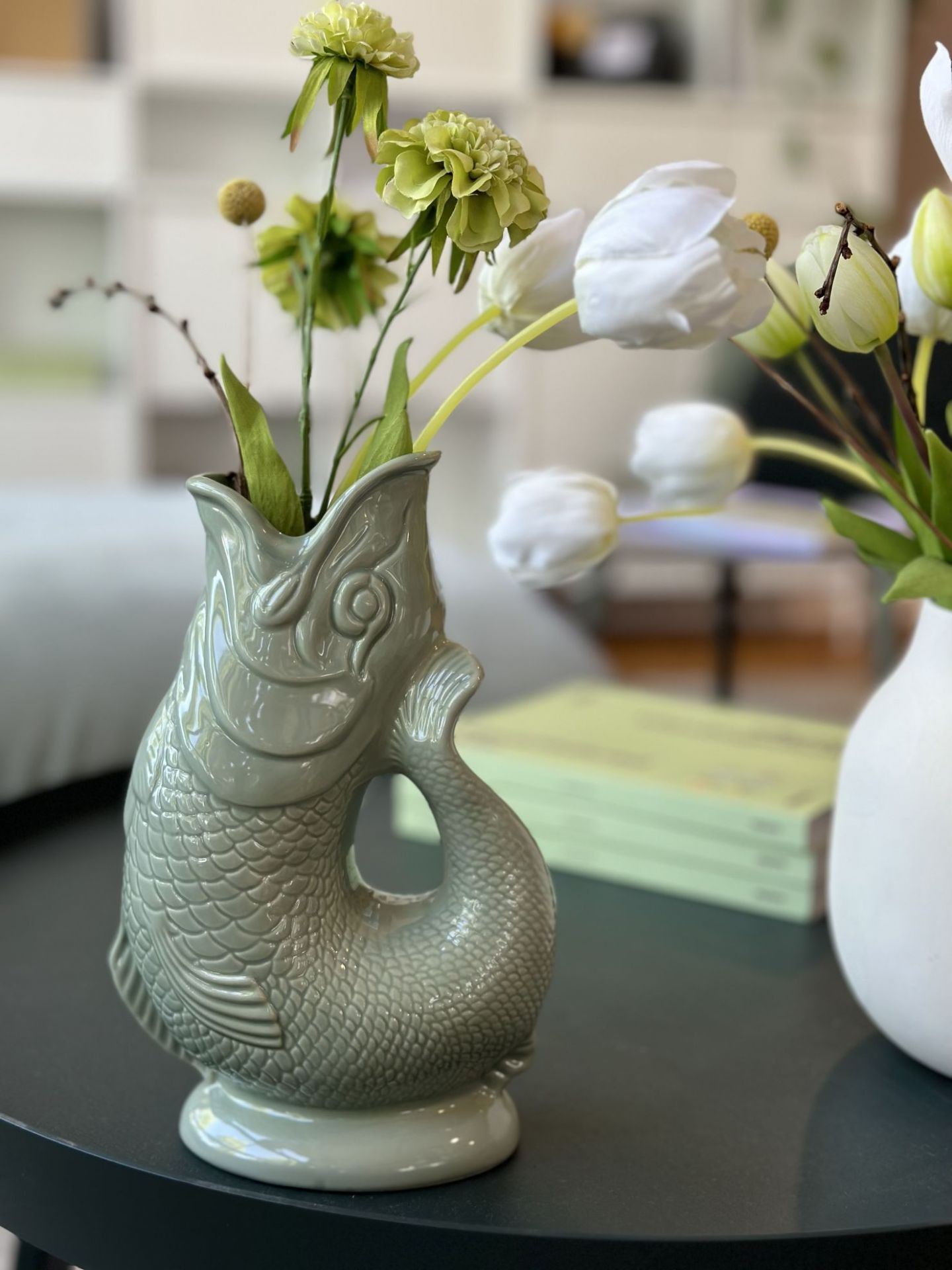 Nahaufnahme der Gluckigluck Karaffe in Salbeigrün XL, gefüllt mit Blumen, als dekorative Vase.