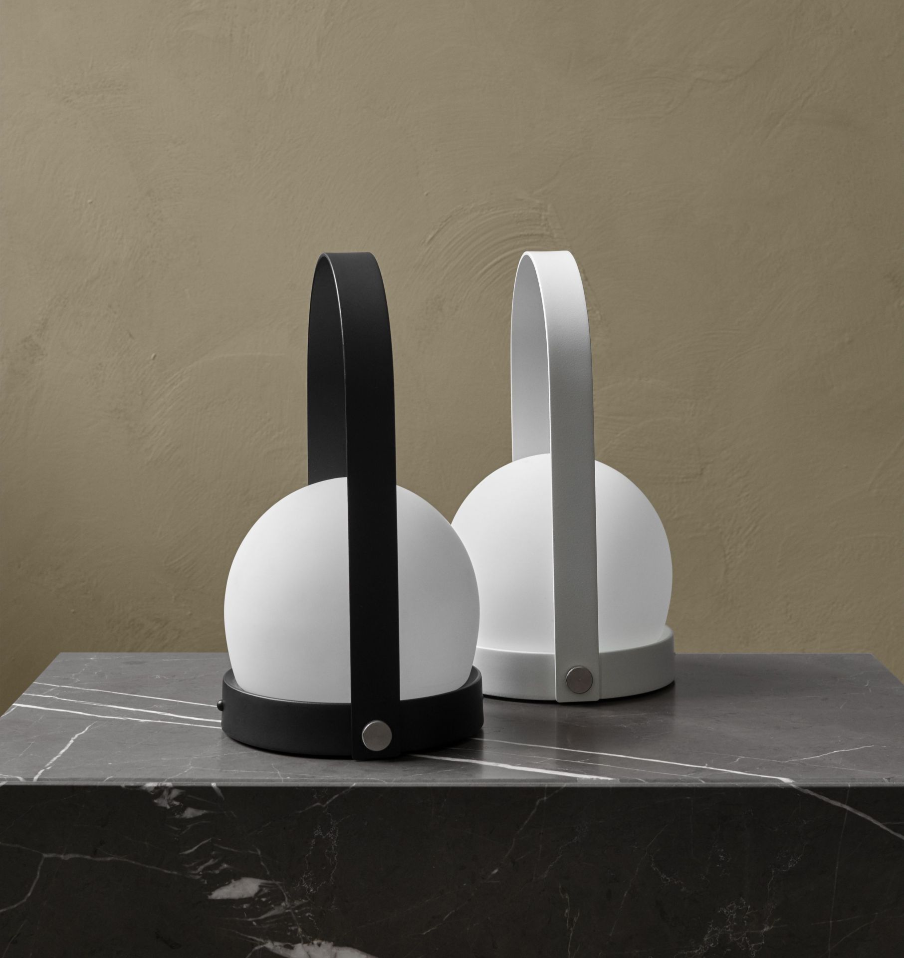 Zwei Carrie Tischleuchten: Eine schwarze und eine weiße Akkuleuchte auf einem Marmortisch.