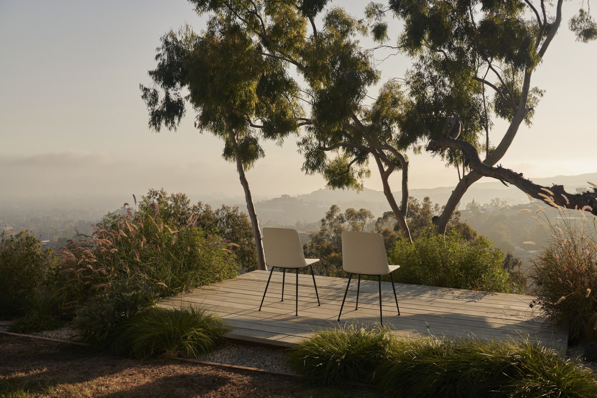 Zwei Rely HW70 Outdoor Stühle von AndTradition auf einer Holzterrasse mit Ausblick.