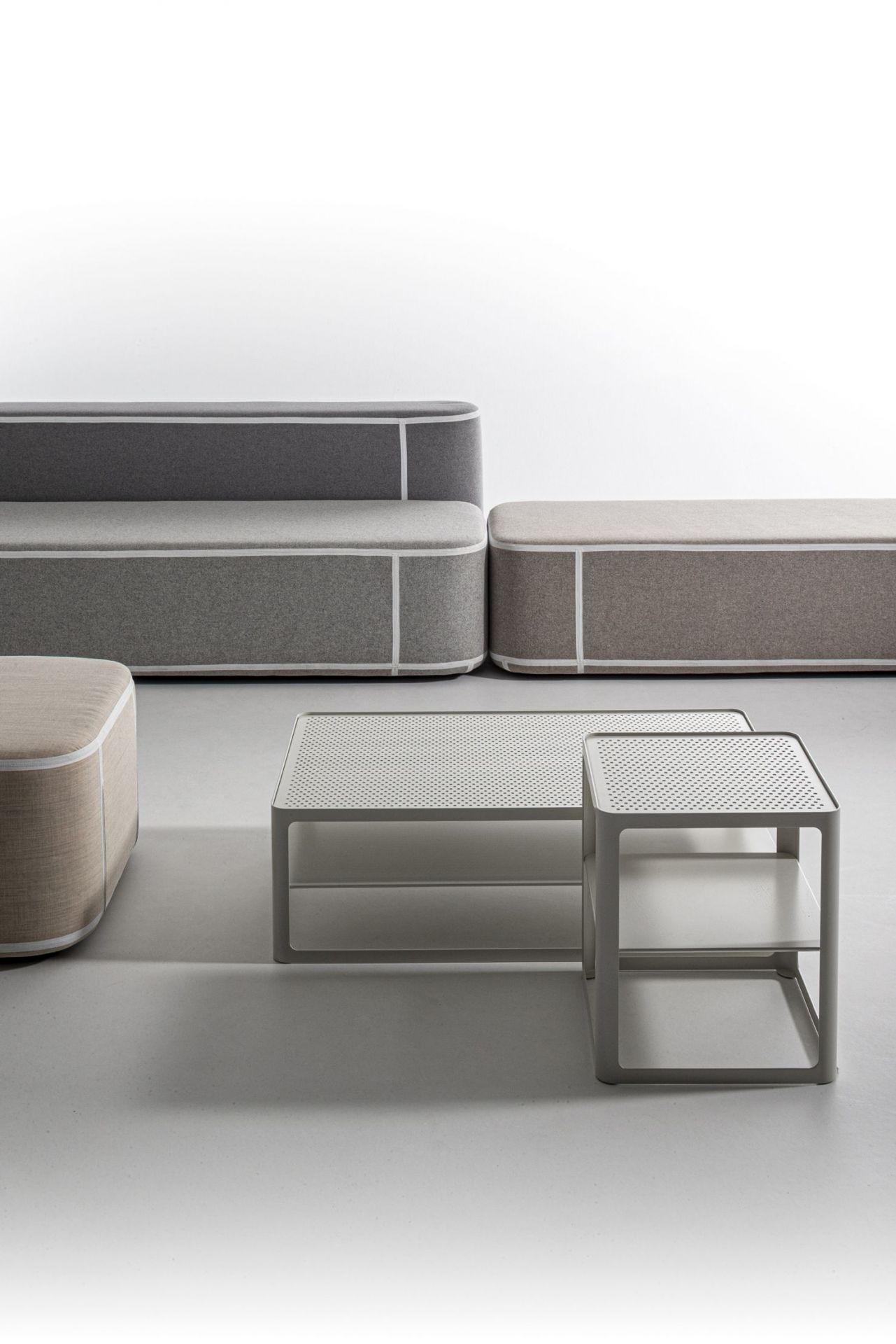 Tape Sofatisch von Moroso und modulare Sofas in Grau- und Beigetönen mit weißer Akzentuierung.