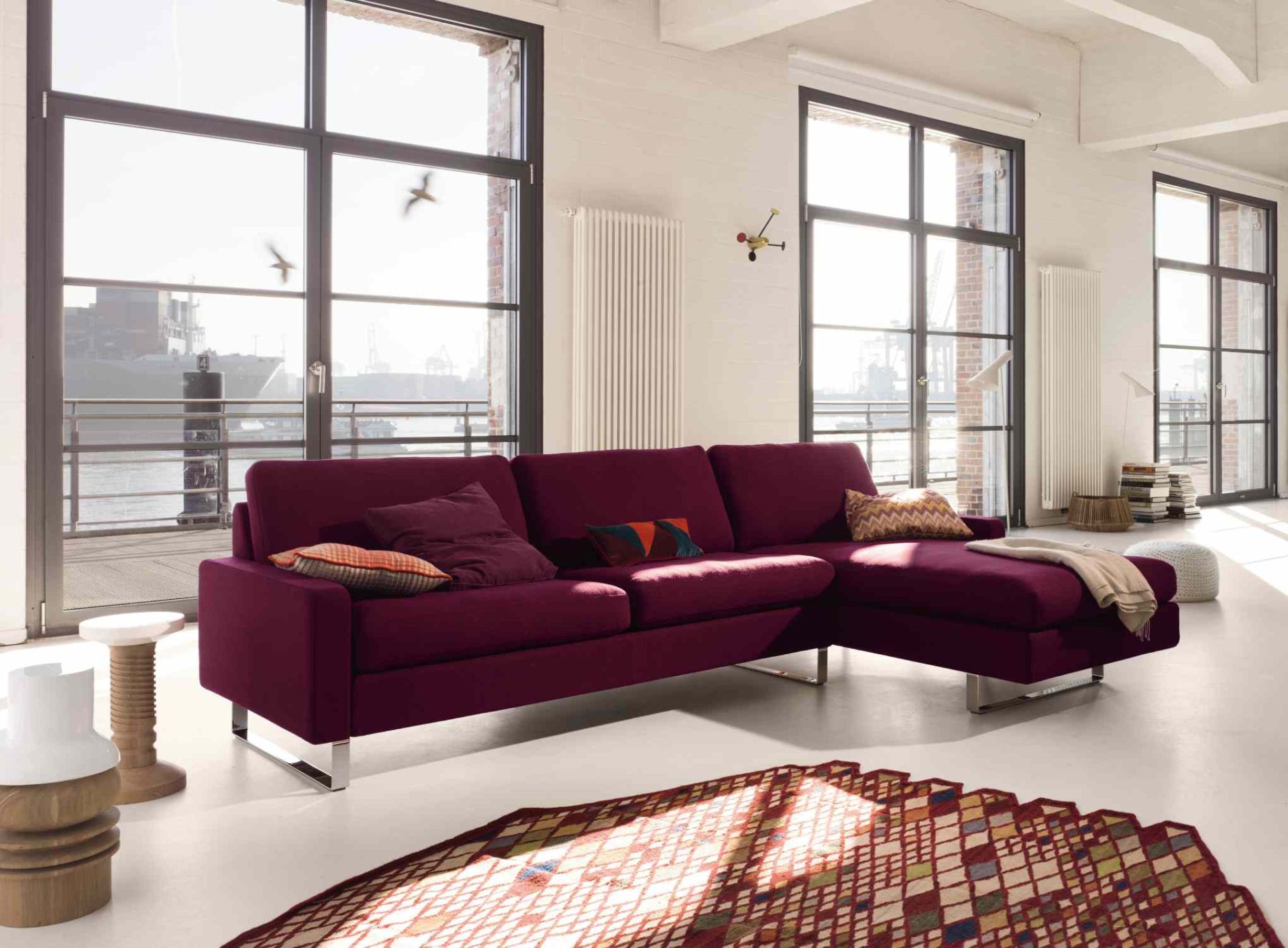 Conseta Sofa von Cor in Lila mit Kissen und Metallfüßen in modernem Wohnzimmer.