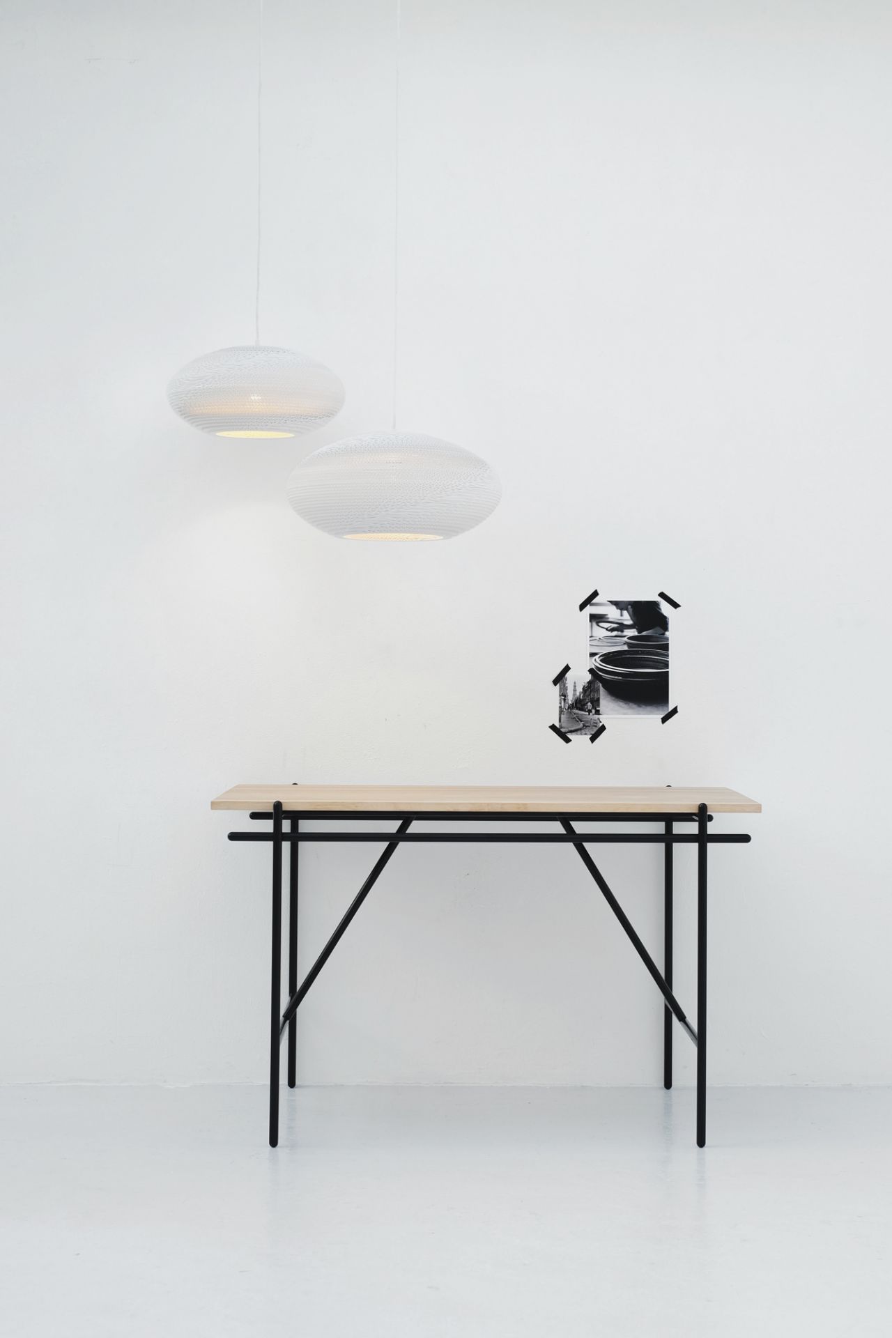 Zwei weiße Scraplights Disc Hängeleuchten von Graypants über einem Tisch mit schwarzem Gestell.
