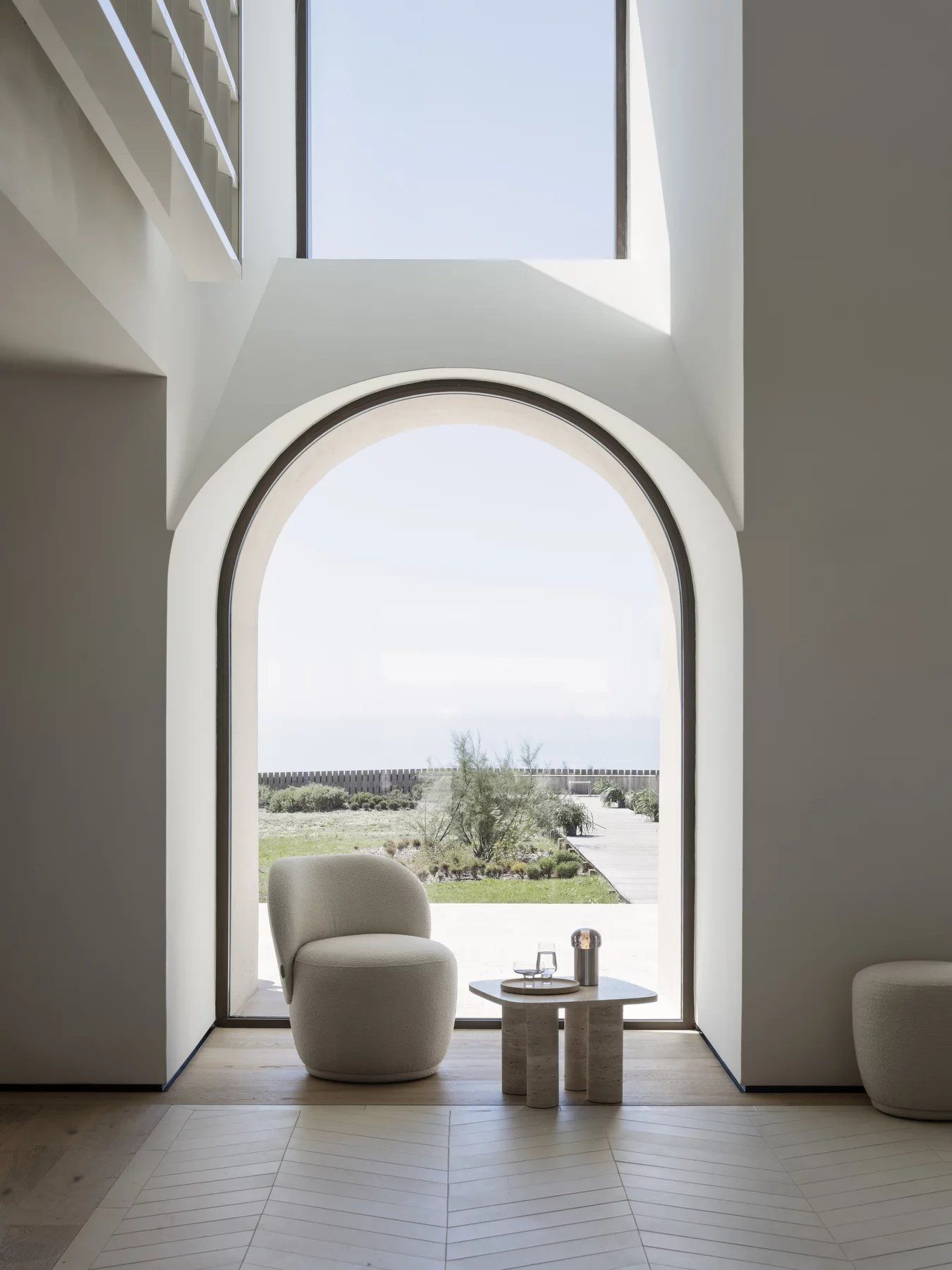 Blomus Volos Beistelltisch aus Travertin in modernem Wohnzimmer mit Sessel und großem Fenster.