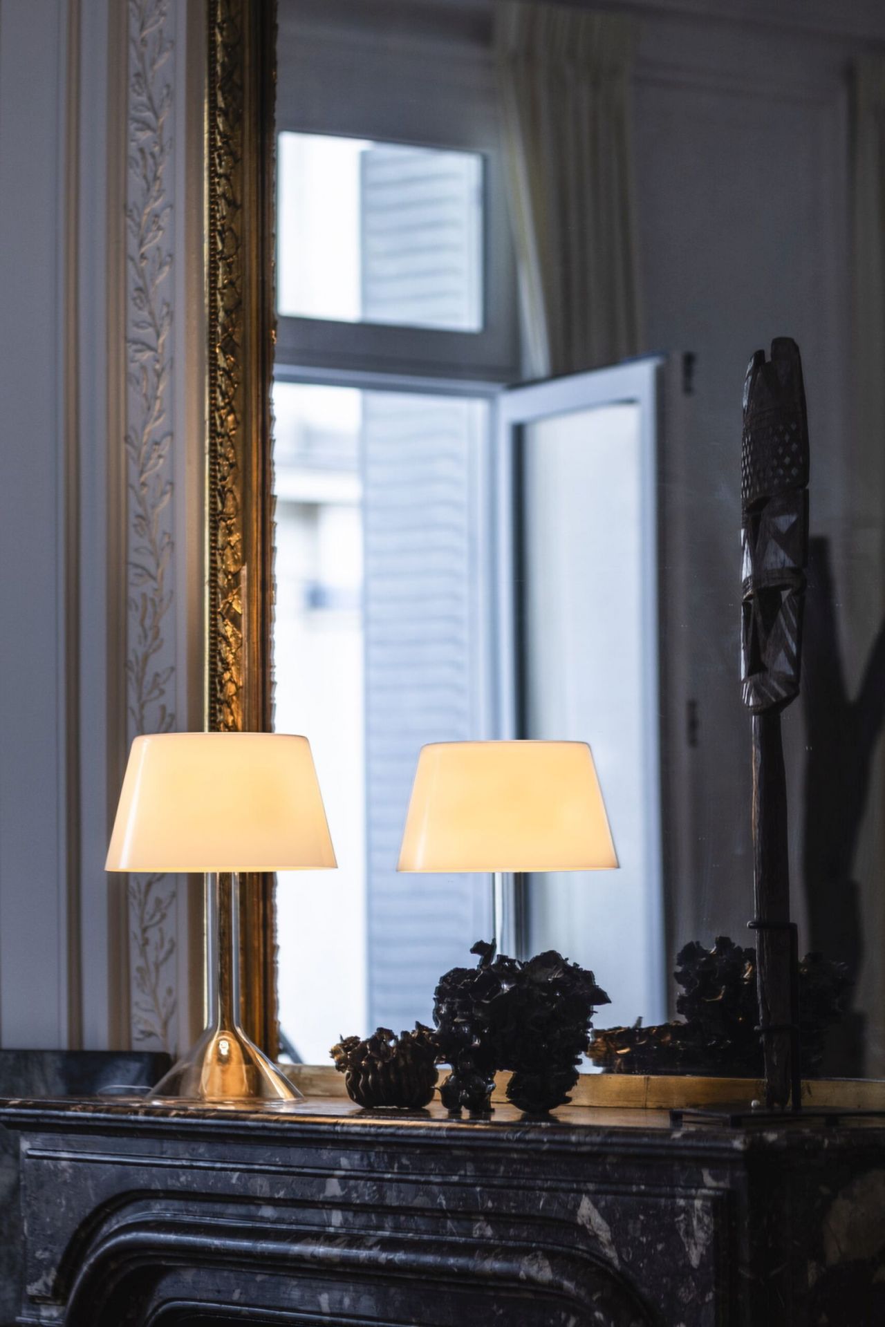 Zwei Chapeaux Tischleuchten von Foscarini mit warmweißem Licht auf einem Marmorkamin.