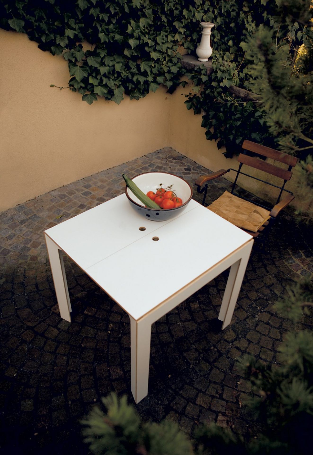 Weißer Klapptisch von Nils Holger Moormann im Garten, mit Schale Tomaten und Gurke.