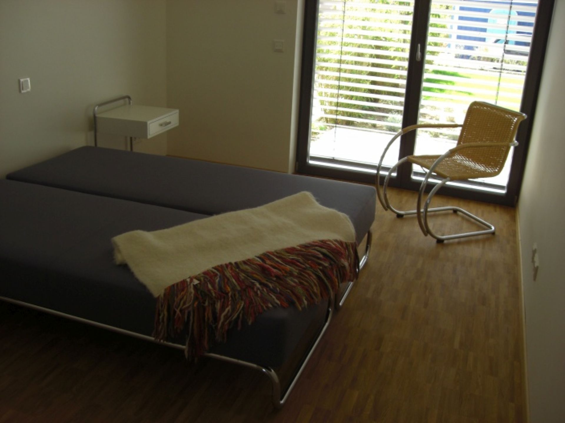 B 117 Beistelltisch von Thonet, weiß lackiert, mit praktischer Schublade neben einem Bett.