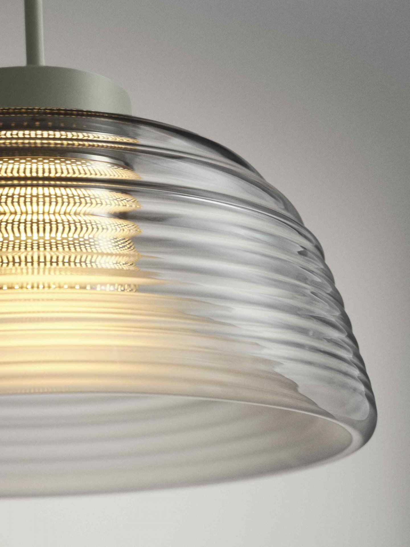 Detailaufnahme der Muuto Two-Layer Pendelleuchte mit geriffeltem Glas und warmem Lichtschein für stimmungsvolle Innenbeleuchtung.