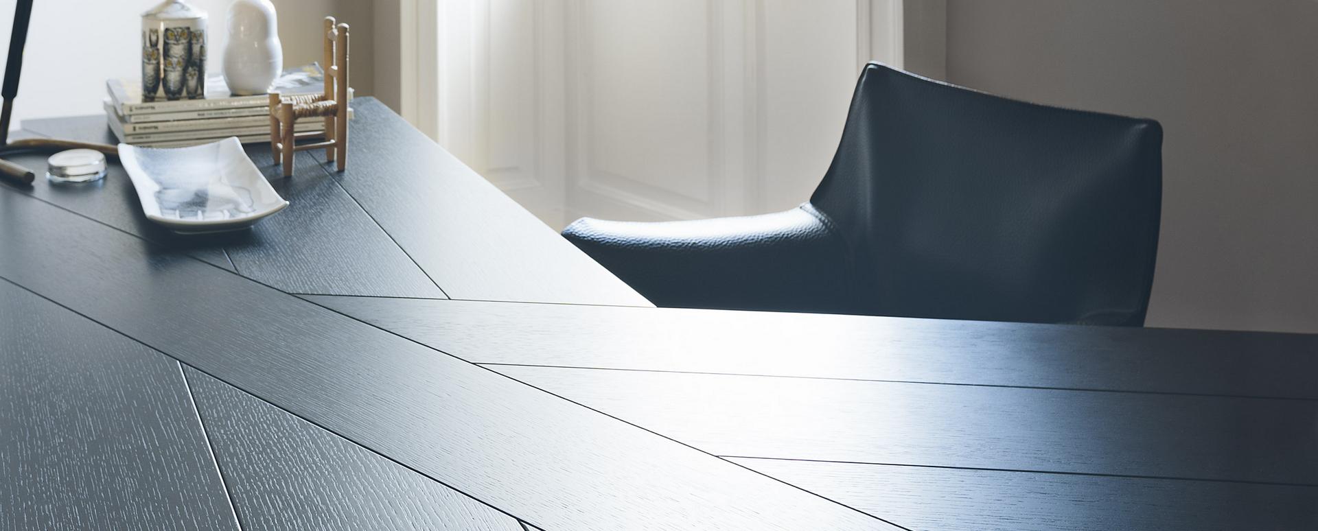 Nahaufnahme des Cassina Cab Armchair Stuhls mit Armlehnen in dunklem Leder am Esstisch.