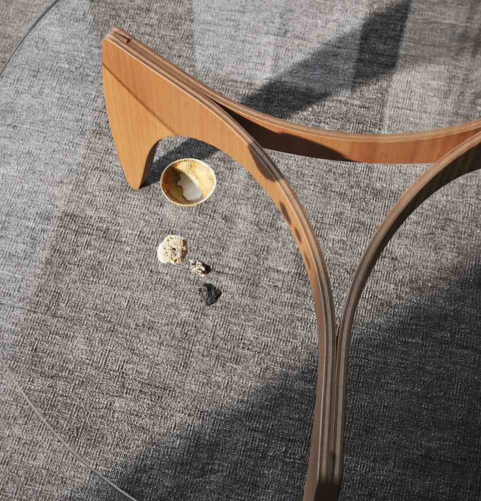 Detailaufnahme des Fritz Hansen PK60 Couchtisches mit Glasplatte und Holzgestell auf grauem Teppich.