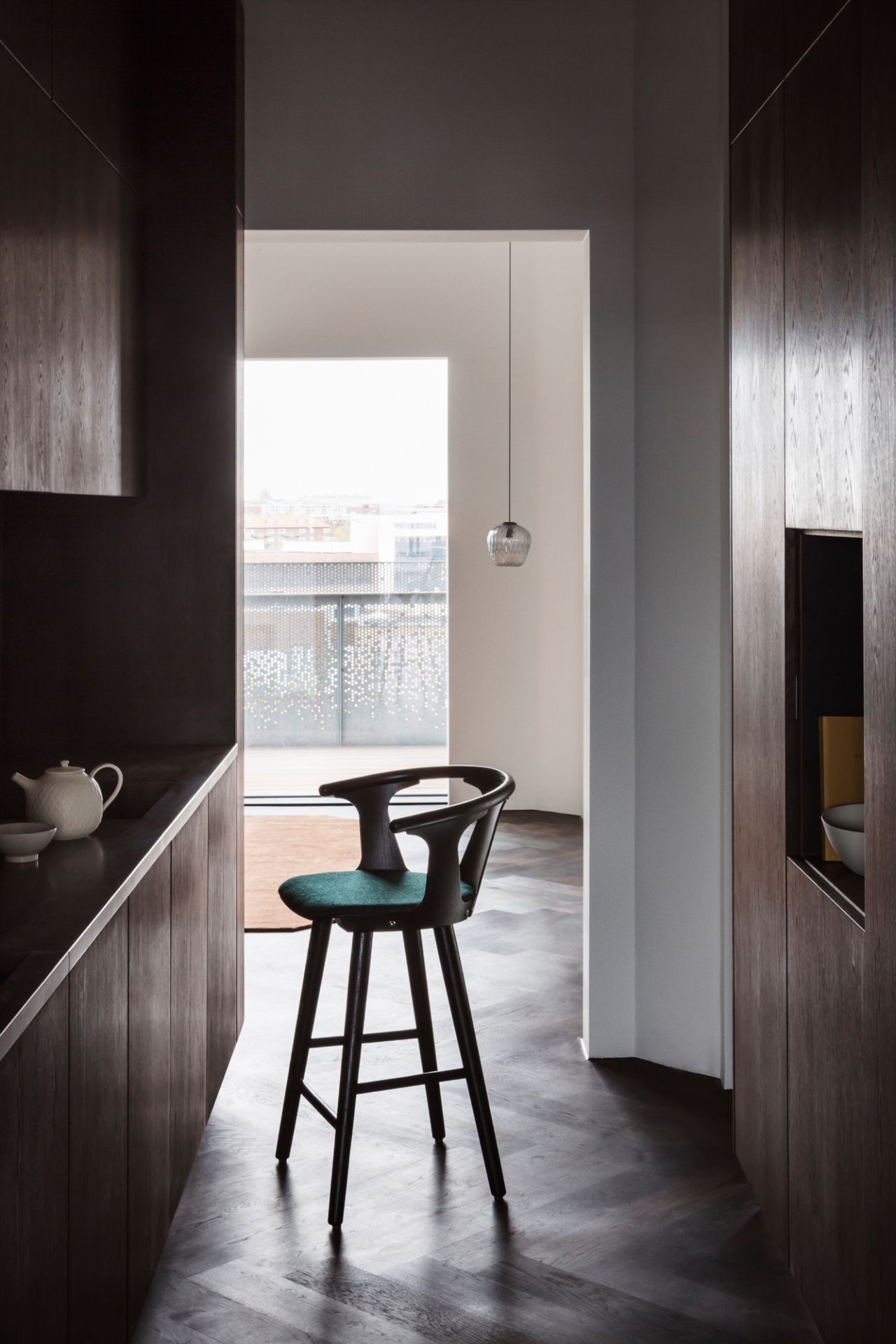 AndTradition Blown Pendelleuchte über Barhocker in moderner Küche mit dunklen Holzschränken und Parkettboden.