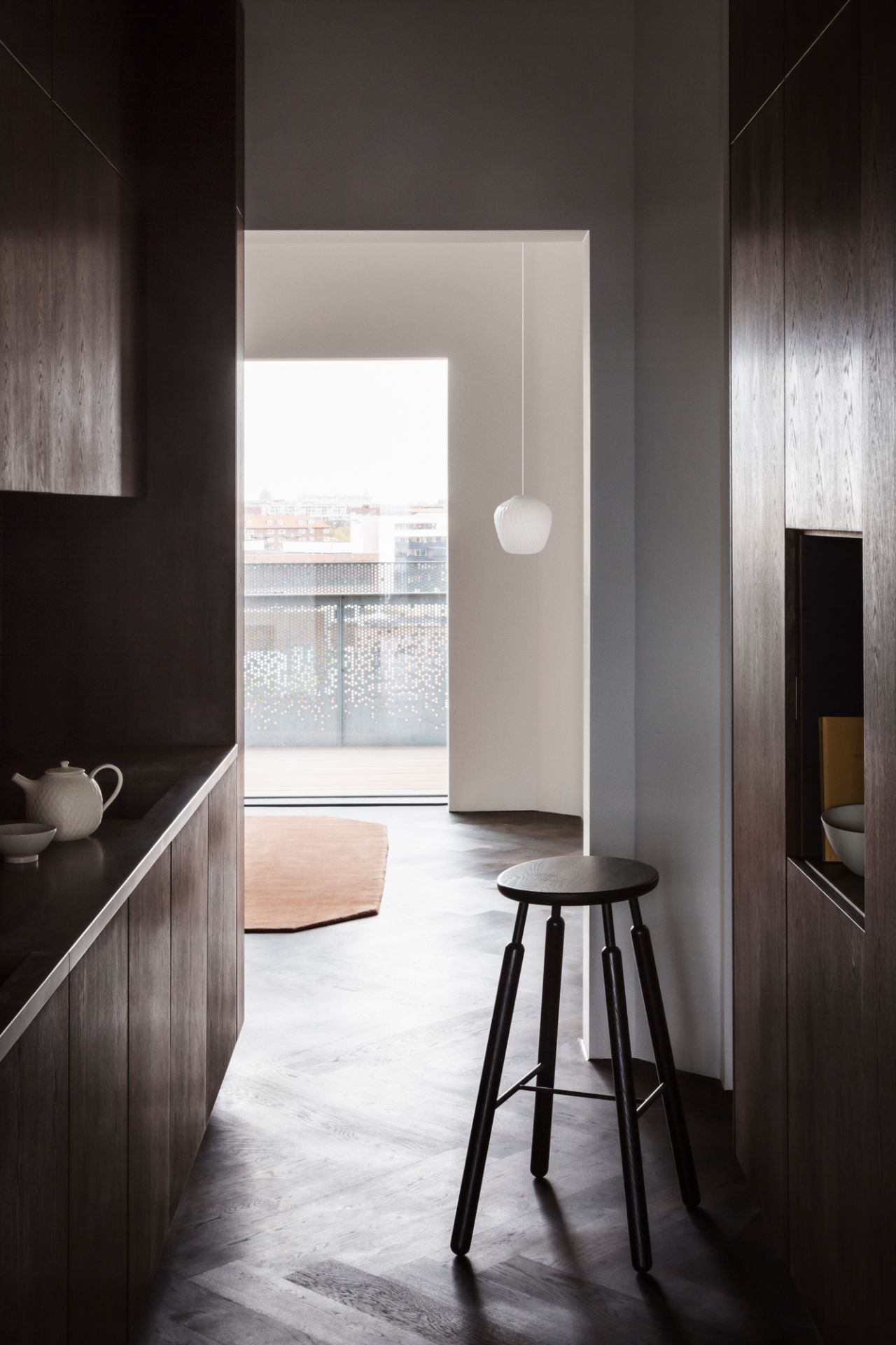 Moderne Küche mit AndTradition Blown Pendelleuchte, die über einem Hocker in minimalistischem Interieur hängt.