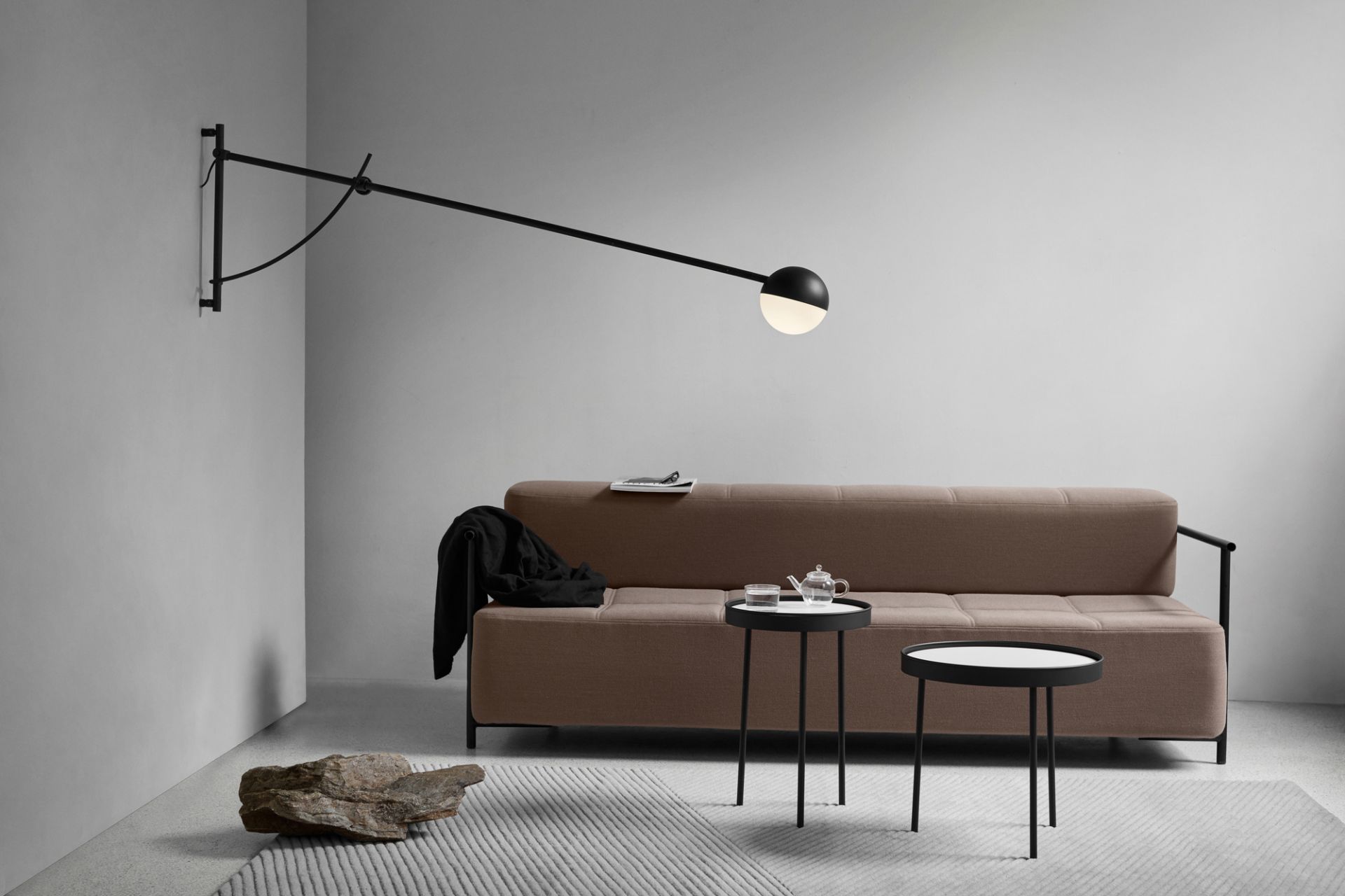 Moderne Balancer Wandleuchte von Northern in Schwarz über Sofa, minimalistisches Design für Wohnzimmer.