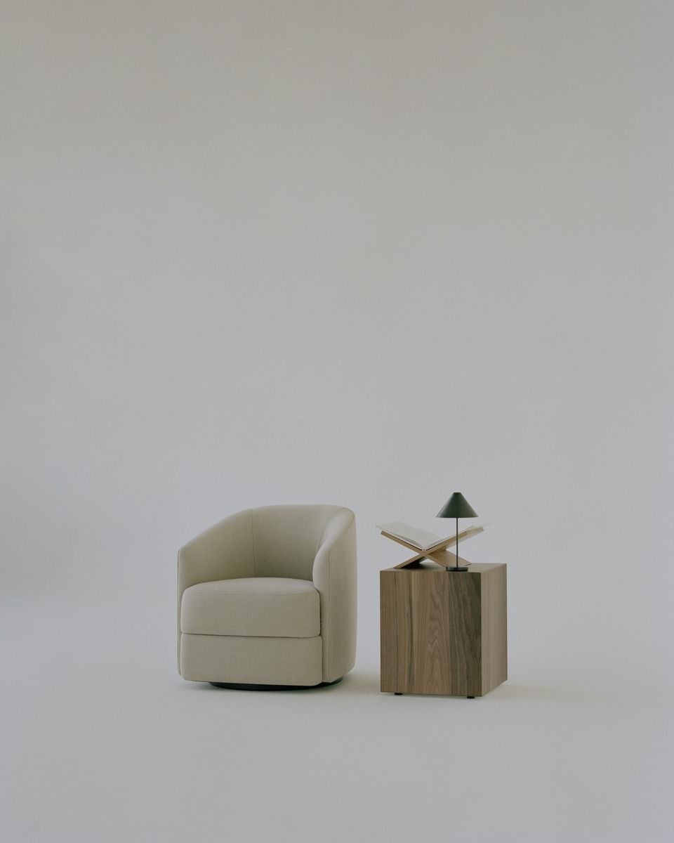Beiger Covent Lounge Chair Sessel von New Works neben einem Holztisch mit Lampe.