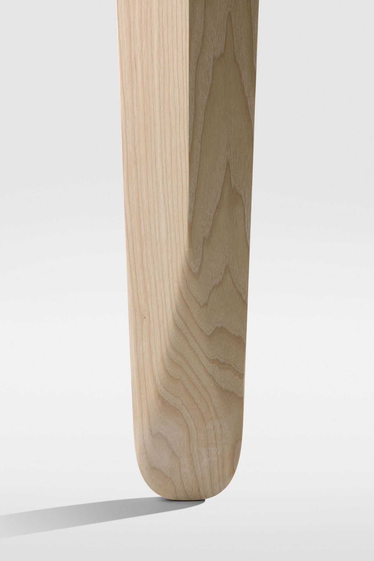 Detailaufnahme des Holzbeins vom Kuyu Dine Esstisch. Hochwertiger Esstisch mit modernem Design und natürlicher Holzstruktur.