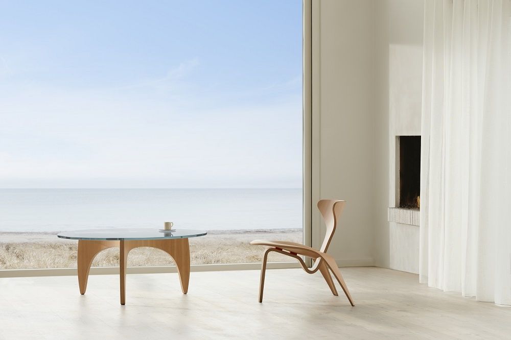 Heller Raum mit PK60 Couchtisch von Fritz Hansen und Holzstuhl vor großem Fenster.