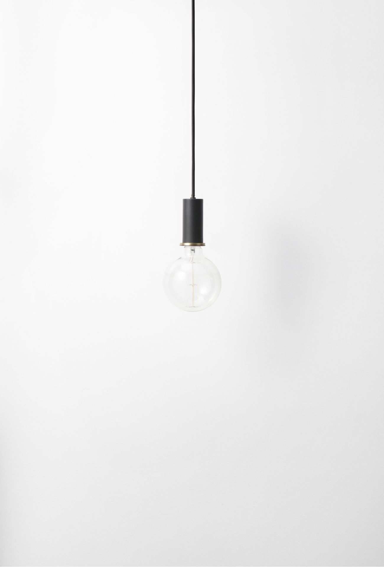 Schwarze Collect Pendelleuchte von Ferm Living mit Glühbirne vor weißem Hintergrund. Hängelampe für Wohnraum.