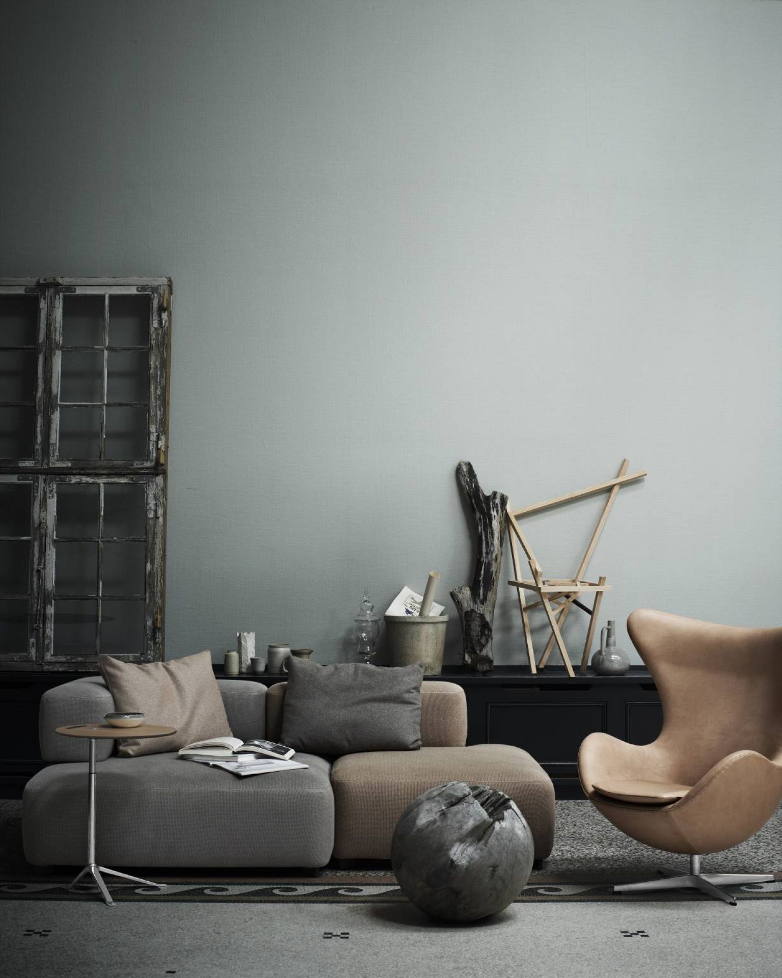 Wohnzimmer-Szene mit Fritz Hansen Little Friend Beistelltisch, Sofa, Sessel und dekorativen Elementen. Minimalistisches Design.