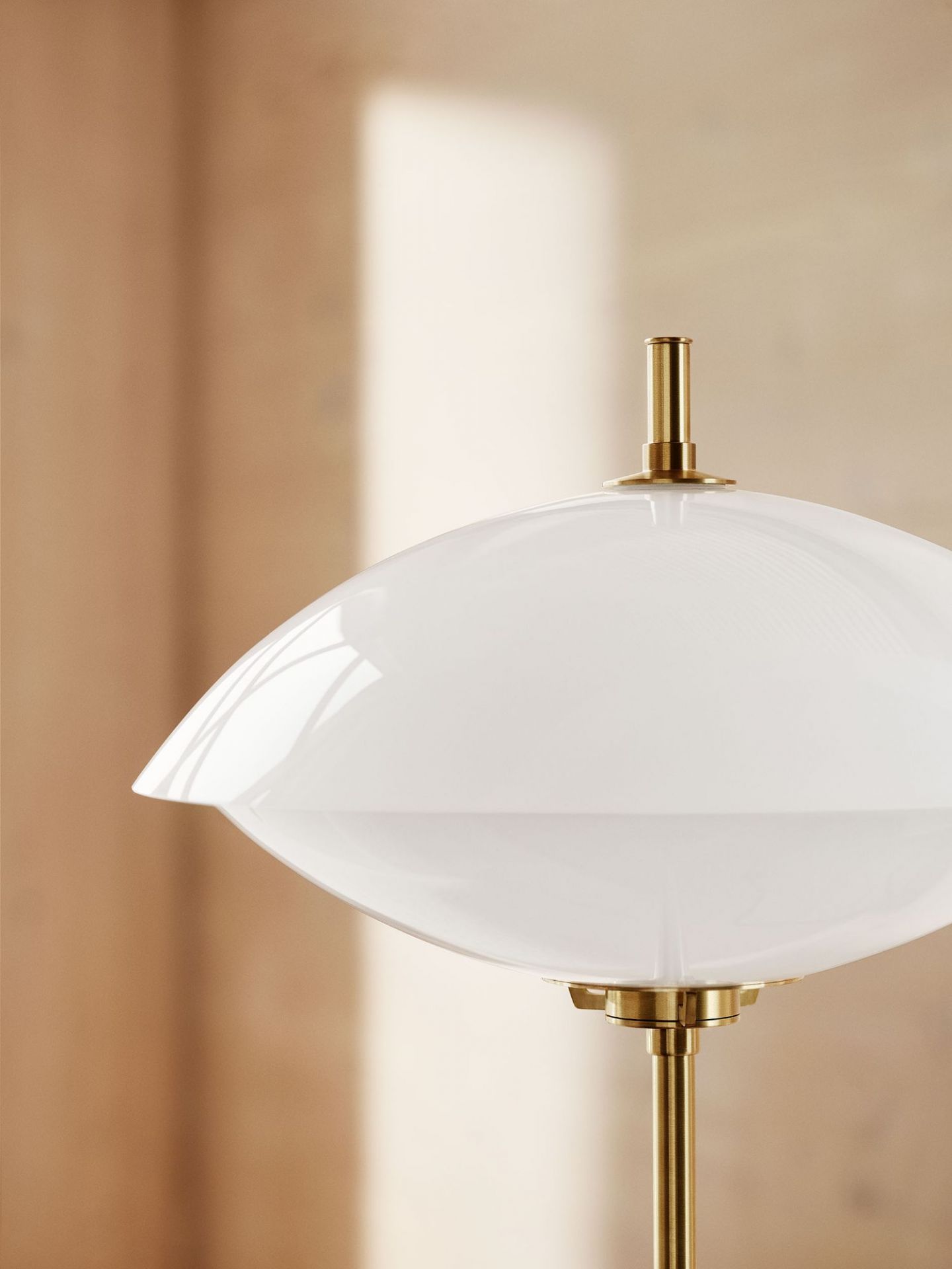 Detailaufnahme der Clam Tischleuchte von Fritz Hansen mit weißem Schirm und goldenem Gestell.