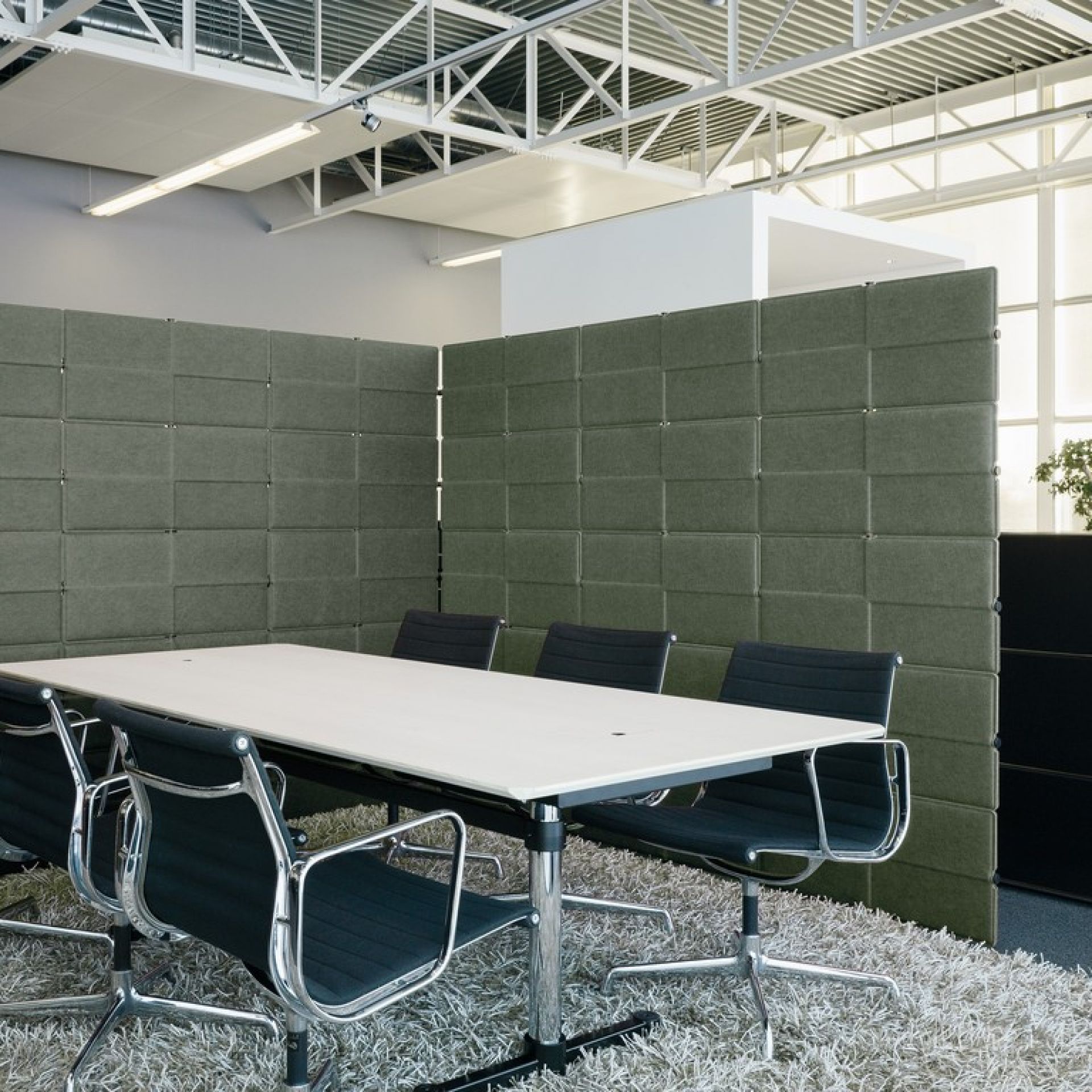 Büro mit USM Haller Trennwänden in Grün, Besprechungstisch und Bürostühlen für mehr Privatsphäre.