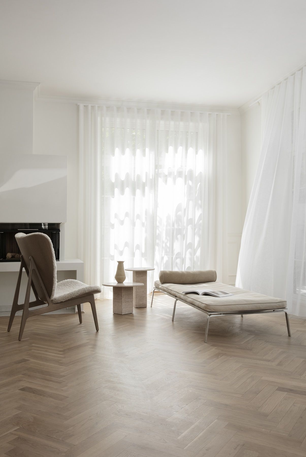 Helles Wohnzimmer mit NORR11 Daybed Liege, Sessel und Beistelltischen auf Parkettboden.