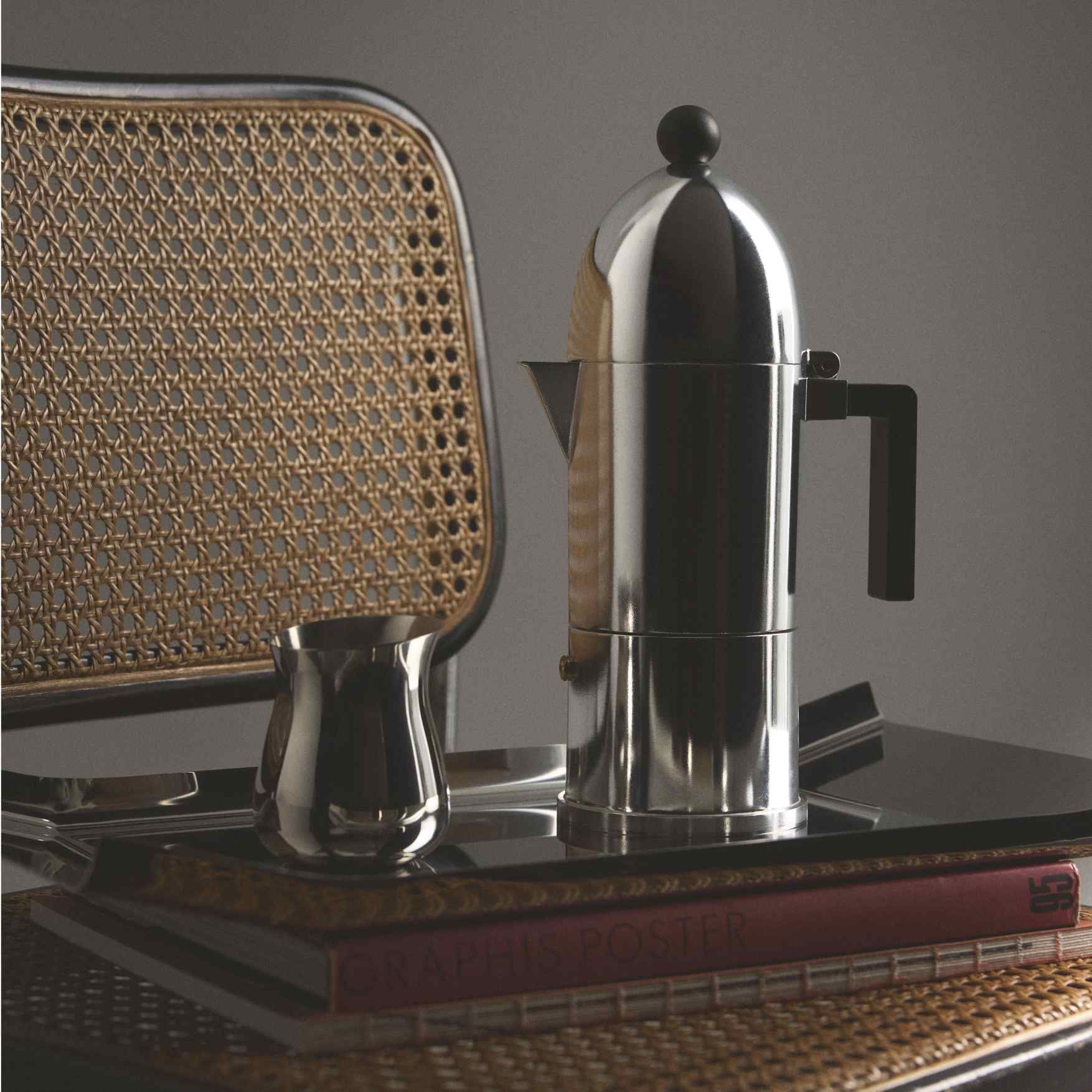 Alessi La Cupola Espressokocher, schwarzer Griff, auf Tisch mit Milchkanne. Italienische Kaffeekultur.