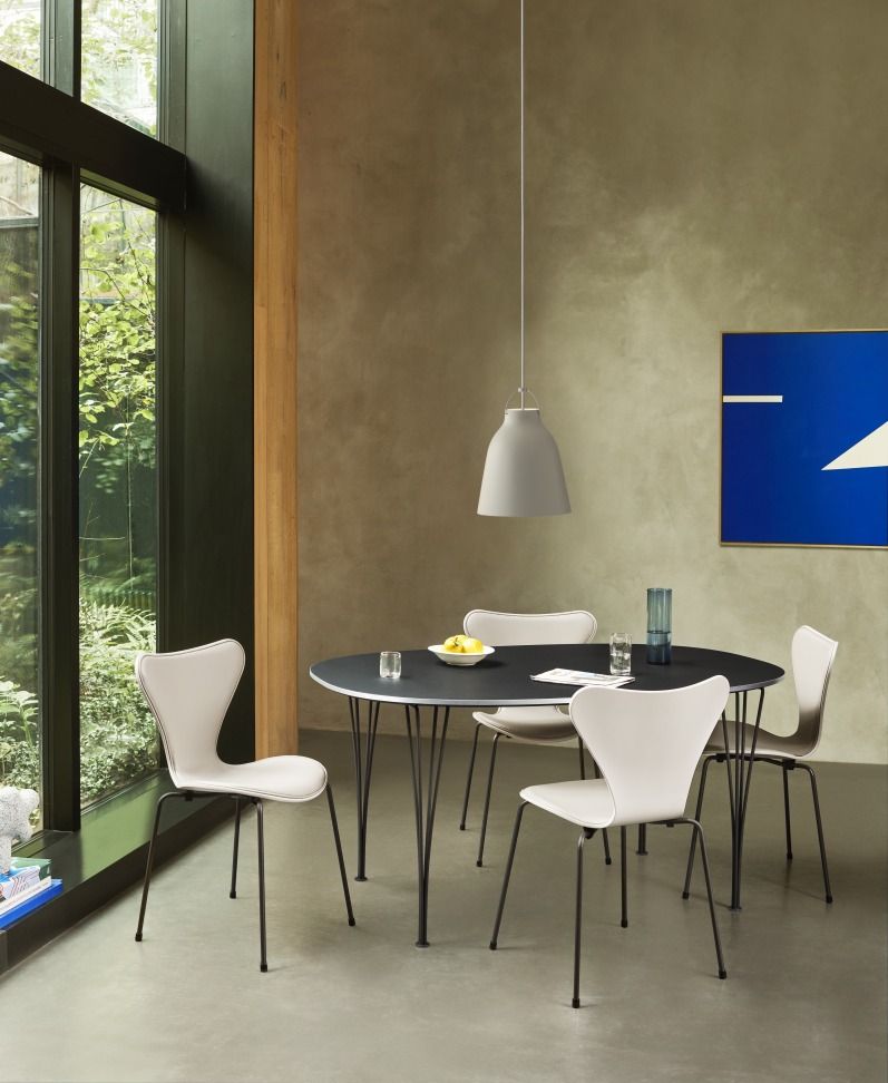 Graue Caravaggio Pendelleuchte von Fritz Hansen über Esstisch mit Stühlen in modernem Interieur.